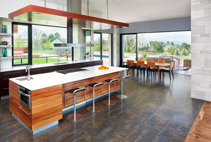 The mellow tones of the applewood island and the richness of the subtly metallic floor tile from Porcelanosa warm the modern kitchen. To keep the well-used space looking sleek and uncluttered there’s a serparate “scullery” for daily appliances and food storage. Dining table pendant lights are LBL from the Lighting Studio.