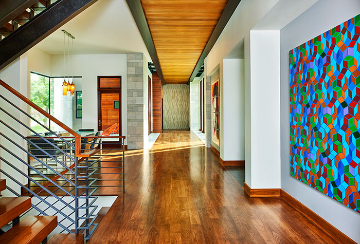 The first-floor hallway leads to a large hidden mudroom.  The geometric painting is Quantum Zone by Colorado artist Clark Richert.