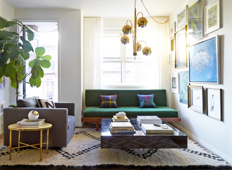 A Moroccan rug anchors the living area, which features a vintage brass Arc light fixture, a Jonathan Adler lacquer block cocktail table, and a midcentury daybed upholstered in velvet.